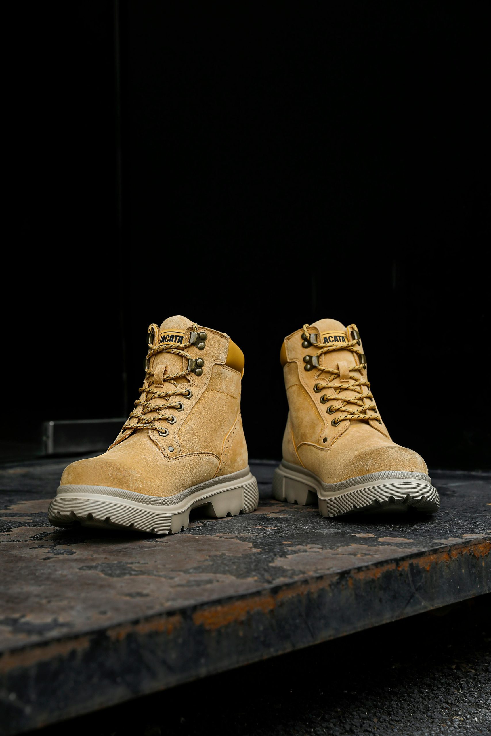 Pair of rugged work boots on a gritty surface, showcasing durability.